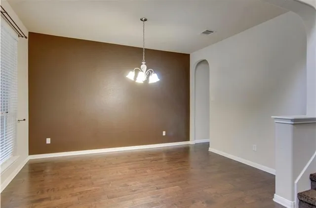 a view of an empty room with chandelier fan and refrigerator