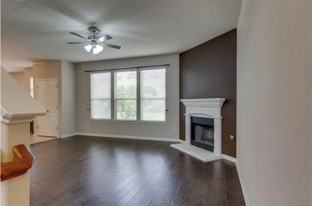 a view of an empty room with wooden floor fireplace and a window