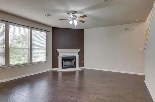 an empty room with windows fireplace and wooden floor