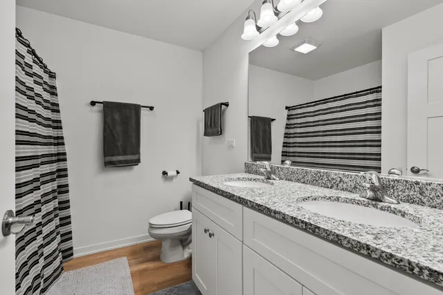 a bathroom with a granite countertop sink a large mirror and toilet