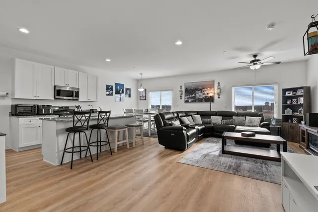 a living room with furniture kitchen view and a wooden floor