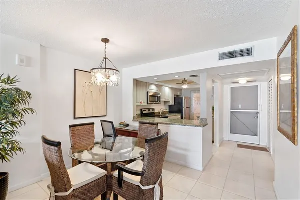 a dining room with furniture a chandelier and kitchen view