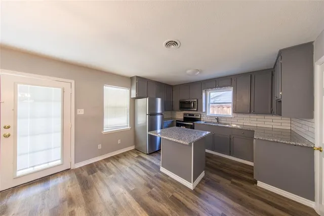 a kitchen with granite countertop a refrigerator stove and oven