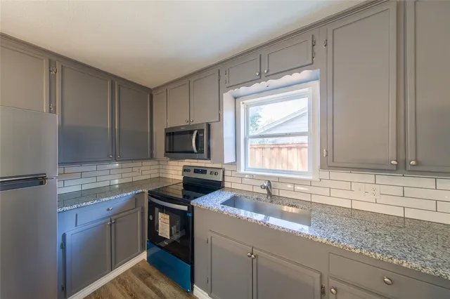 a kitchen with stainless steel appliances granite countertop a stove a sink and a refrigerator