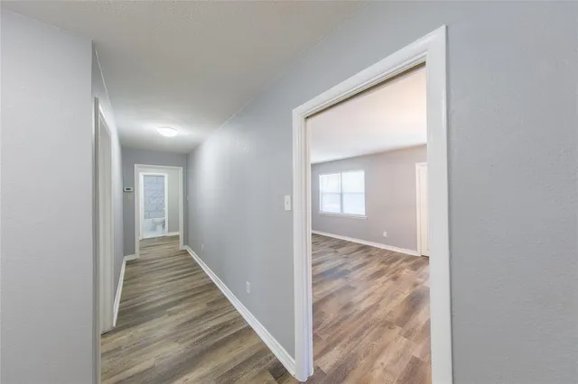 a view of a hallway with wooden floor and a bathroom
