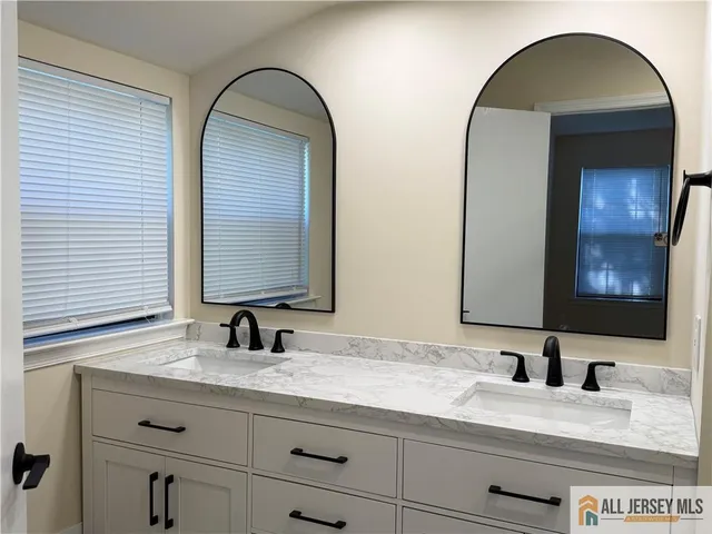 a bathroom with a granite countertop double vanity sink and mirror