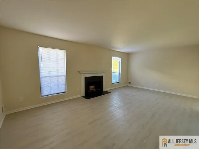 an empty room with windows and fireplace