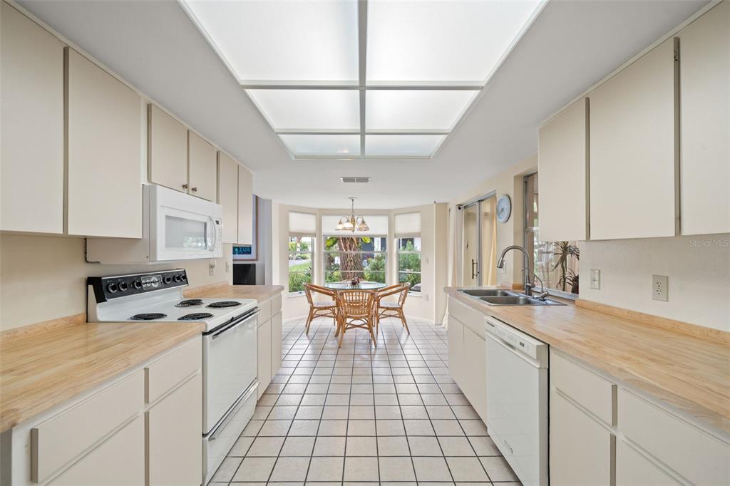 6404 Lost Tree Lane Spring Hill, FL 34606 - Photo 28 of 63 a large white kitchen with granite countertop a stove a sink a dining table and chairs
