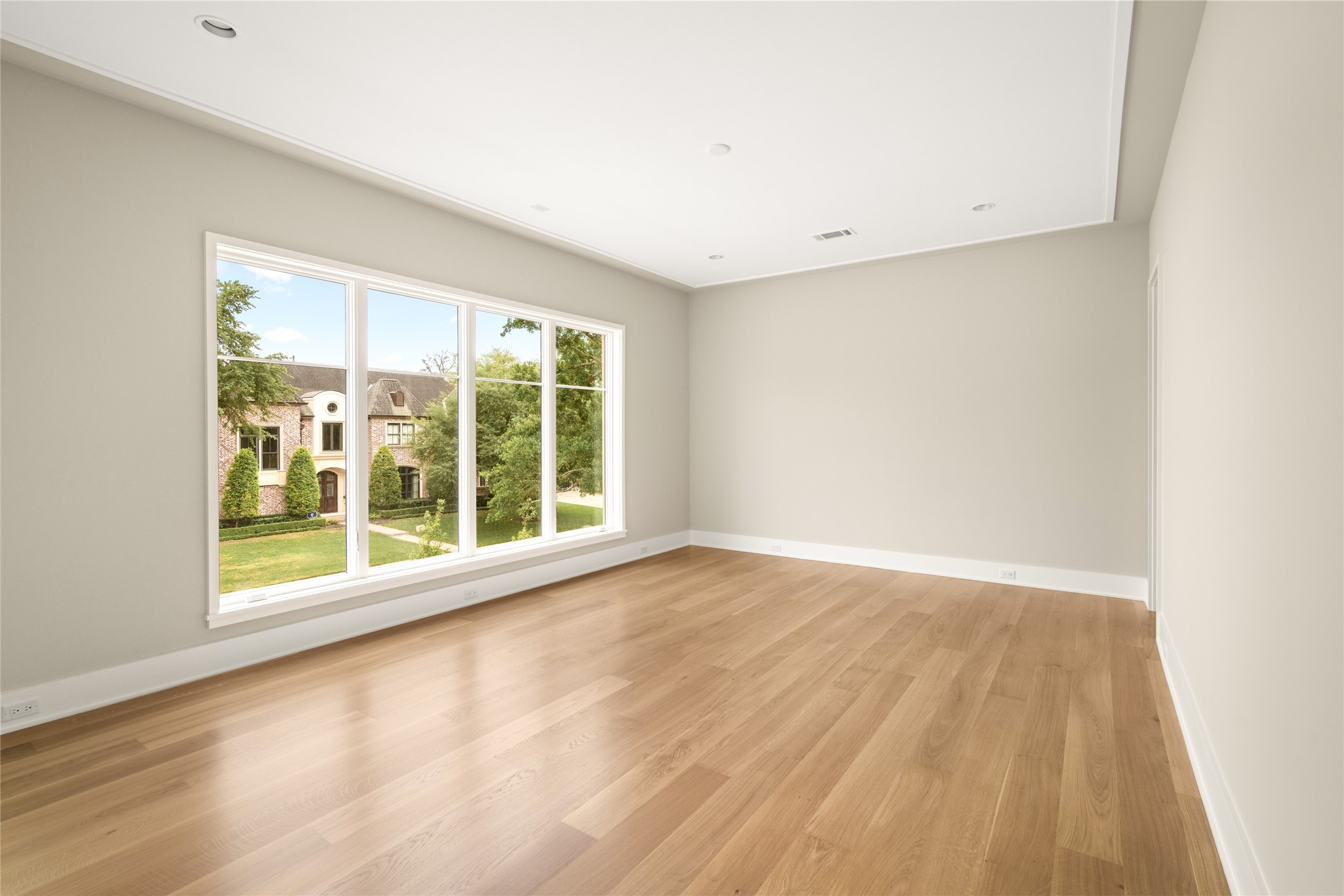 4006 Overbrook Lane Houston, TX 77027 - Photo 38 of 50 Spacious secondary bedroom with the continuation of wide-plank hardwoods seen throughout the home and a wall of windows overlooking the front grounds.