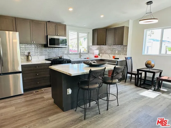 a kitchen with stainless steel appliances a table chairs refrigerator microwave and cabinets