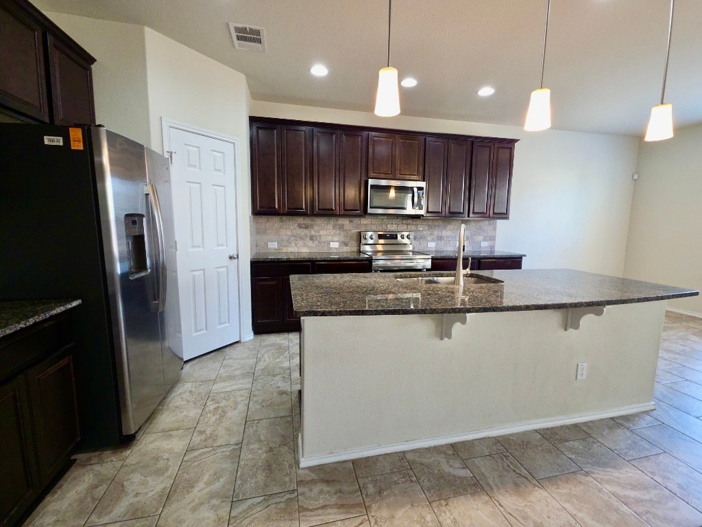 3805 Tranquil Lane Austin, TX 78728 - Photo 12 of 30 a kitchen with stainless steel appliances granite countertop a refrigerator a sink a stove a microwave and wooden cabinets