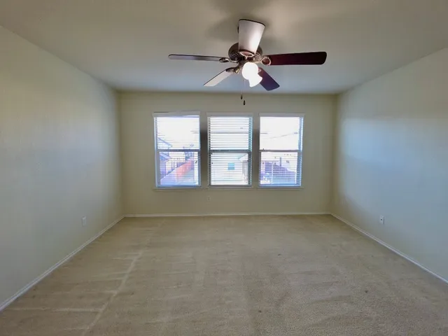 an empty room with windows and ceiling fan