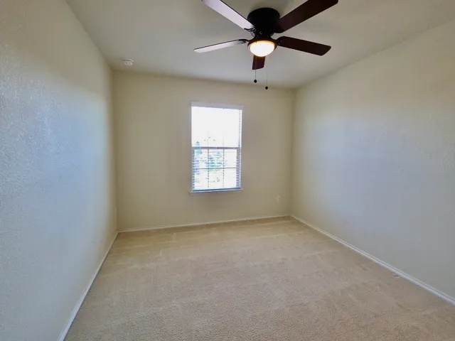 an empty room with a window and a fan