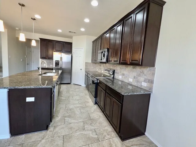a kitchen with stainless steel appliances granite countertop a stove a sink and a refrigerator