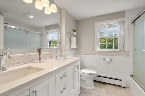 a bathroom with a double vanity sink toilet and a tub