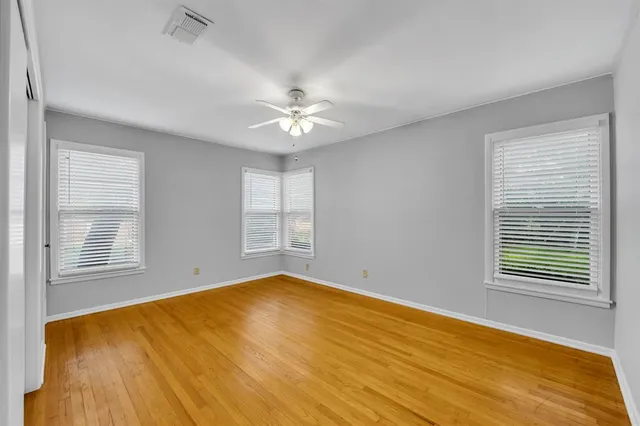 a view of an empty room with a window and wooden floor