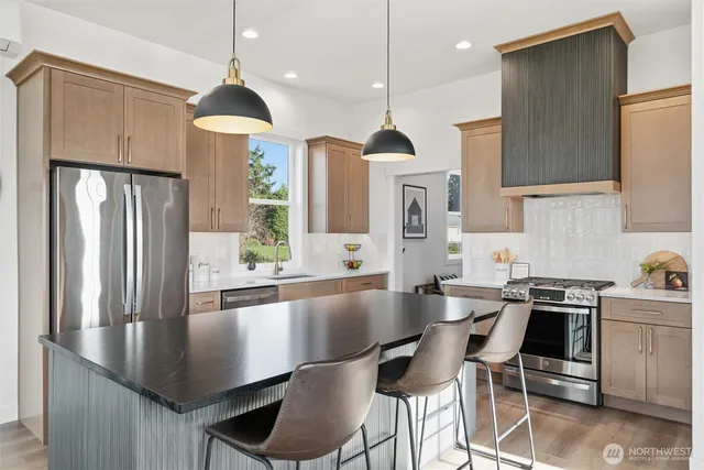 a kitchen with stainless steel appliances granite countertop a sink a stove and a refrigerator
