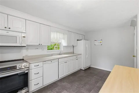 a kitchen with white cabinets and appliances