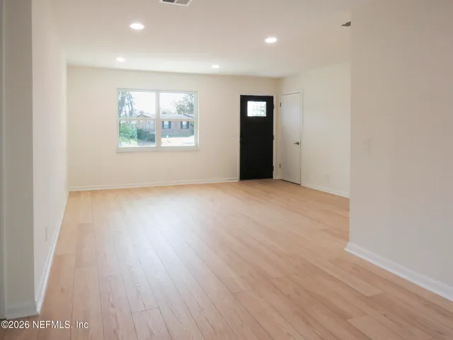 an empty room with wooden floor and windows