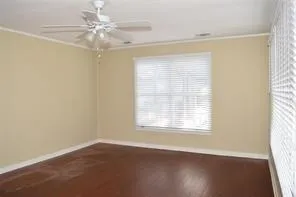an empty room with wooden floor fan and windows