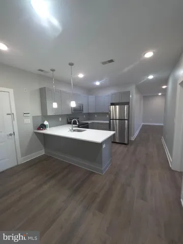 a living room with stainless steel appliances kitchen island a sink dishwasher a refrigerator and a oven with wooden floor