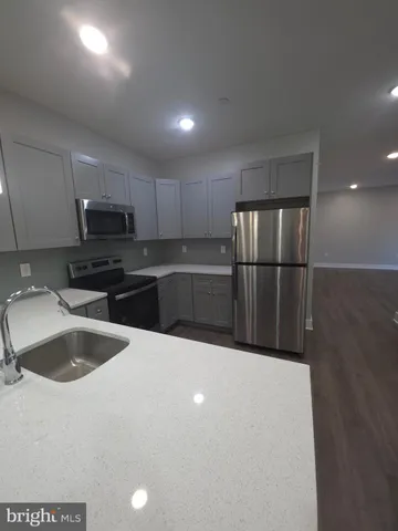 a kitchen with granite countertop a refrigerator a sink and wooden cabinets