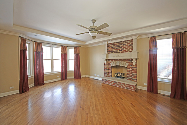 527 Ranch Road Wheaton, IL 60187 - Photo 9 of 25 an empty room with windows a fireplace a ceiling fan and wooden floor