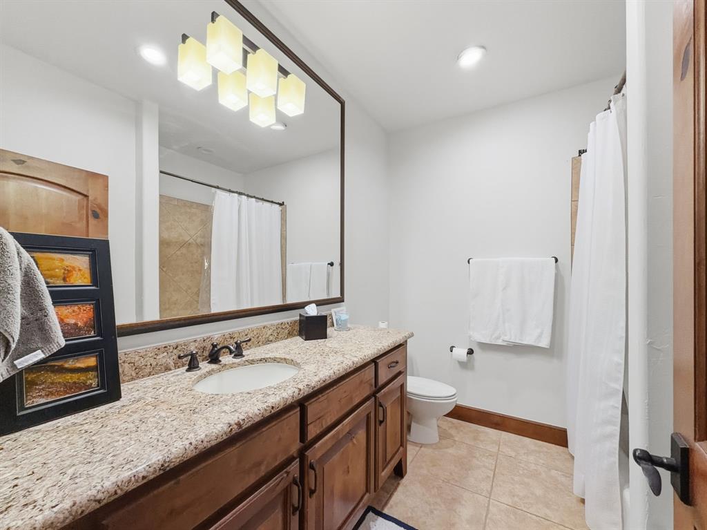 2033 Harbor Way, Unit 302 Graford, TX 76449 - Photo 21 of 28 a bathroom with a granite countertop double vanity sink and a mirror