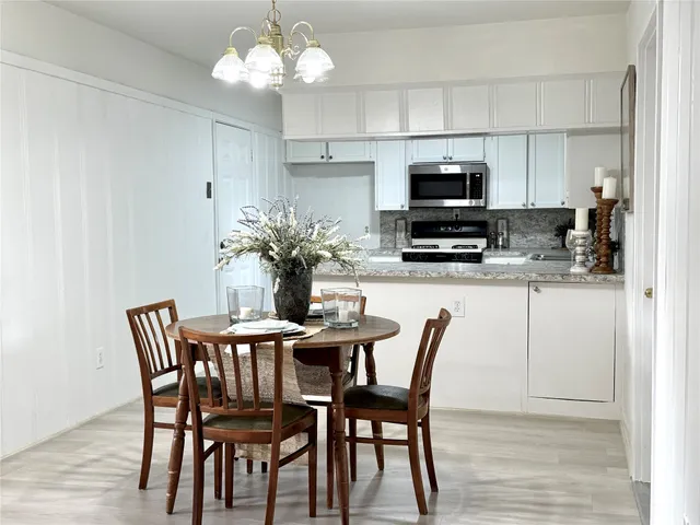 a dining room with furniture a chandelier and kitchen view