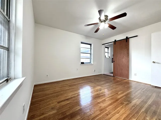 a view of empty room with wooden floor and fan
