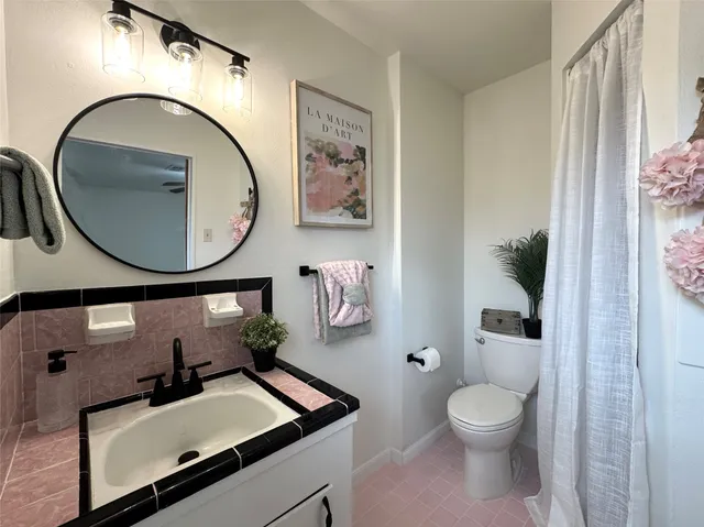a bathroom with a toilet sink vanity tub and mirror