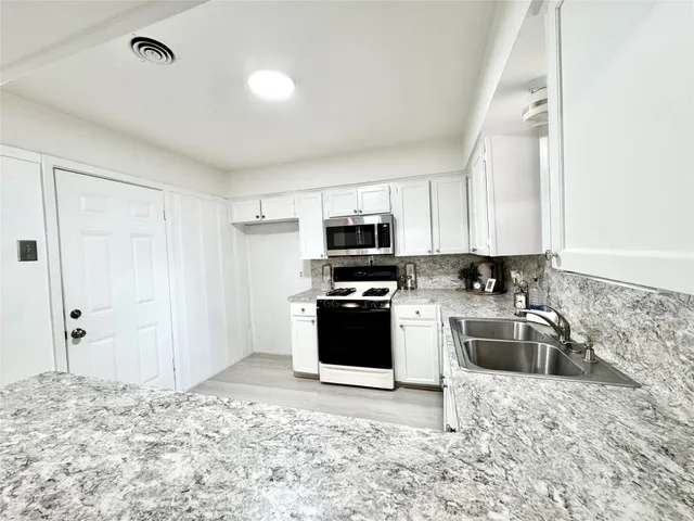 a kitchen with granite countertop a refrigerator and a stove top oven
