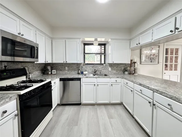 a kitchen with granite countertop white cabinets sink and stainless steel appliances