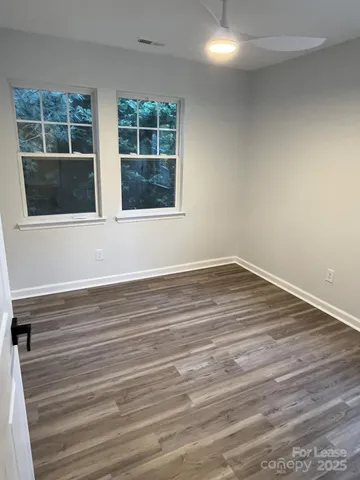 a view of an empty room with a window and wooden floor