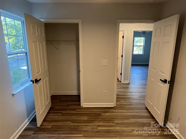 a view of a hallway with wooden floor and closet