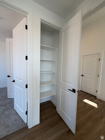 4956 North 925 East, Unit 87 Enoch, UT 84721 - Photo 9 of 19 Integrated pantry featuring white shelving, white door with black hardware, and wood-finish flooring