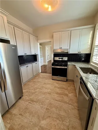 a kitchen with granite countertop a refrigerator stove and sink