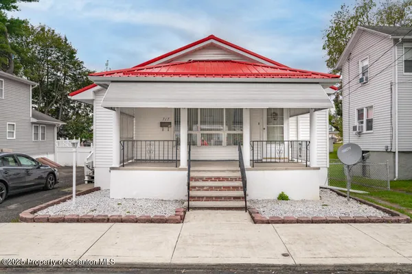 a front view of a house with a yard and potted plants
