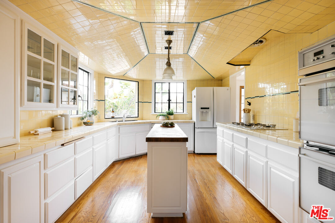 3681 Fairland Boulevard View Park, CA 90043 - Photo 24 of 54 a kitchen with stainless steel appliances a stove a sink dishwasher a refrigerator and white cabinets with wooden floor