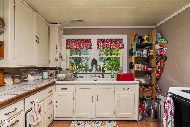 a utility room with cabinets a sink and a window