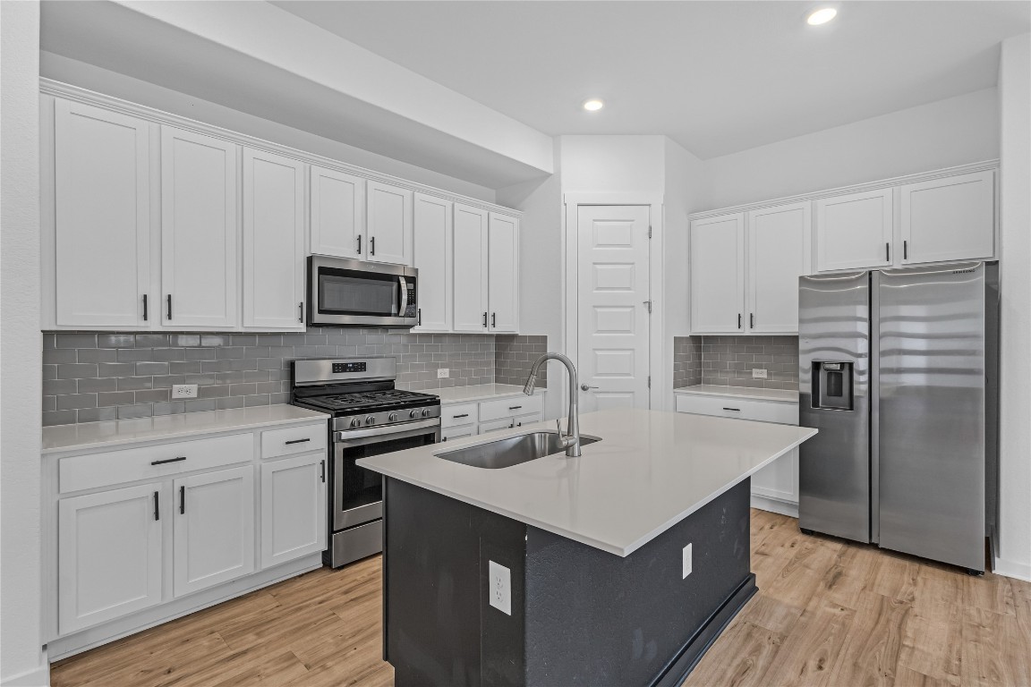 1925 Ruger Pass Leander, TX 78641 - Photo 7 of 26 a kitchen with a sink a stove top oven and white stainless steel appliances