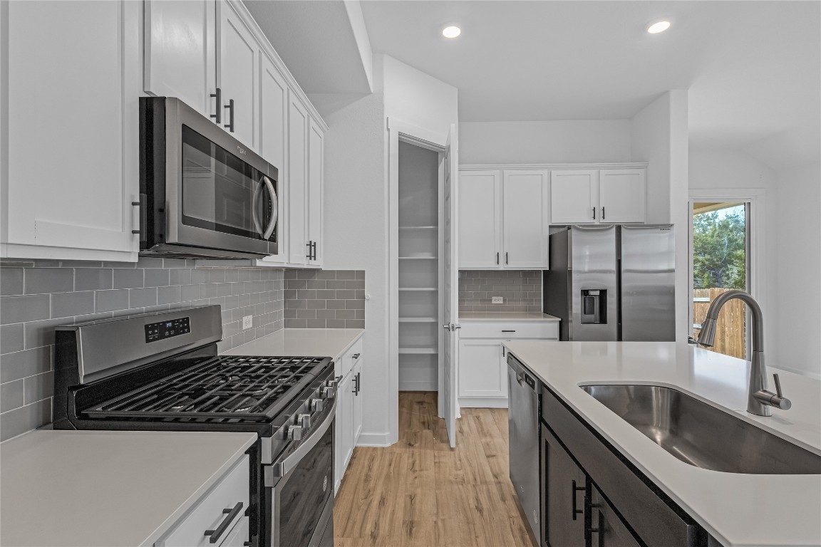 1925 Ruger Pass Leander, TX 78641 - Photo 8 of 26 a kitchen with stainless steel appliances granite countertop a sink stove microwave and refrigerator