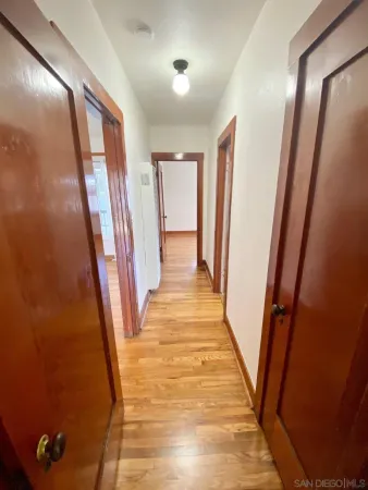 an empty room with wooden floor chandelier fan and windows