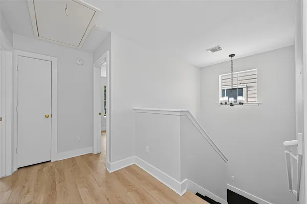 a view of an empty room with wooden floor and window