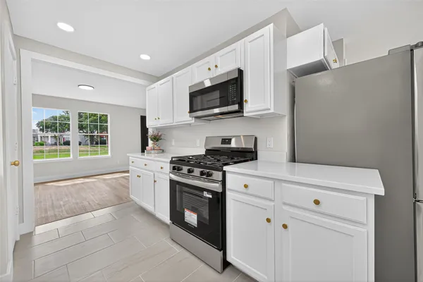 a large kitchen with stainless steel appliances granite countertop a lot of counter space and a sink