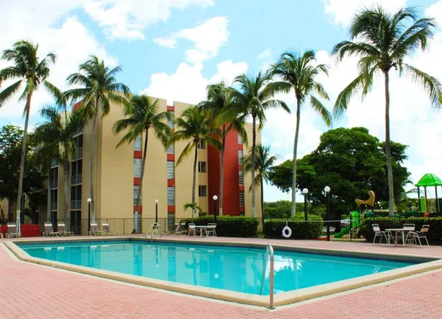 a view of a swimming pool with a garden and palm trees