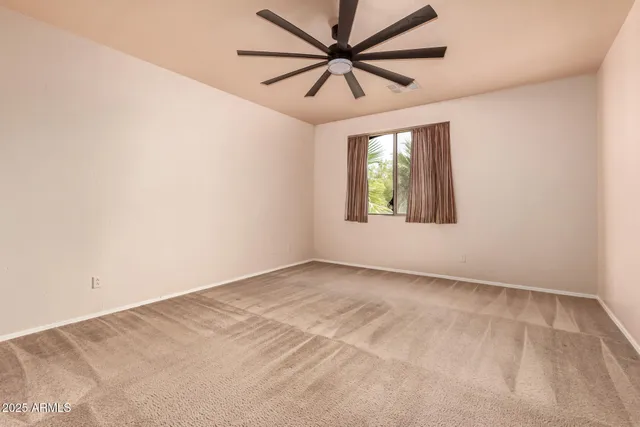an empty room with a window and a ceiling fan