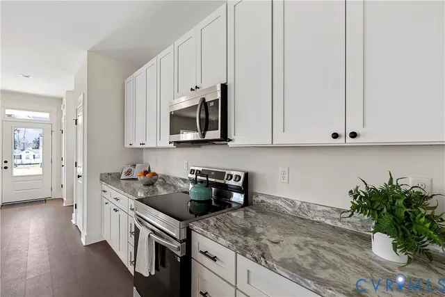 a kitchen with granite countertop a sink a stove and cabinets