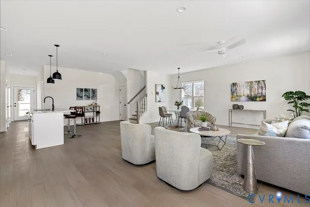 a living room with couches and kitchen view with wooden floor