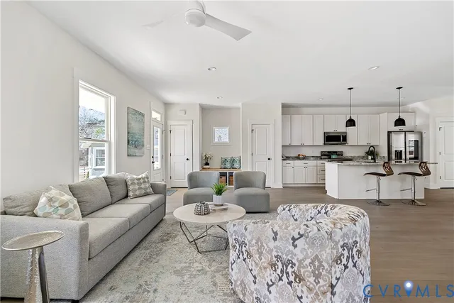 a living room with furniture kitchen view and a large window